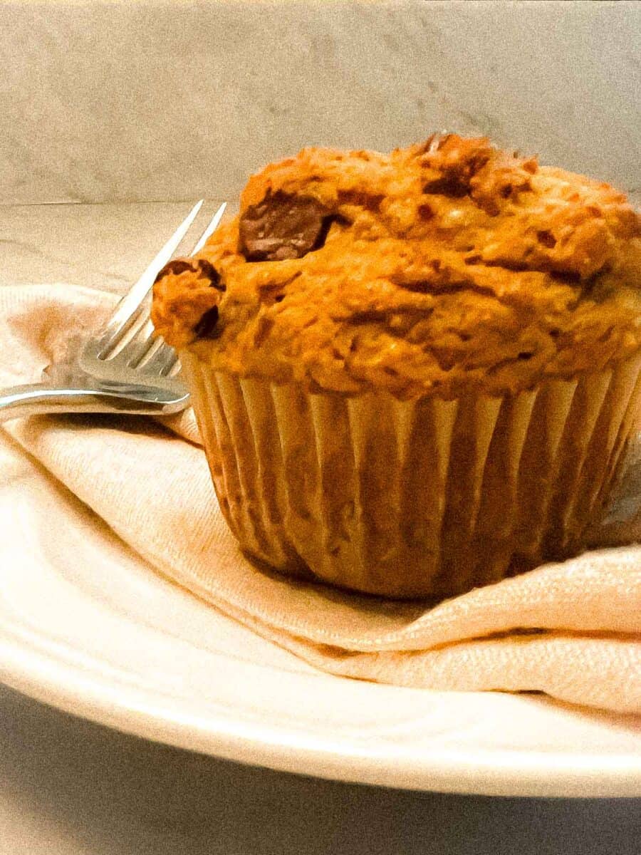 Baked muffin on a white plate with a linen napkin and fork.