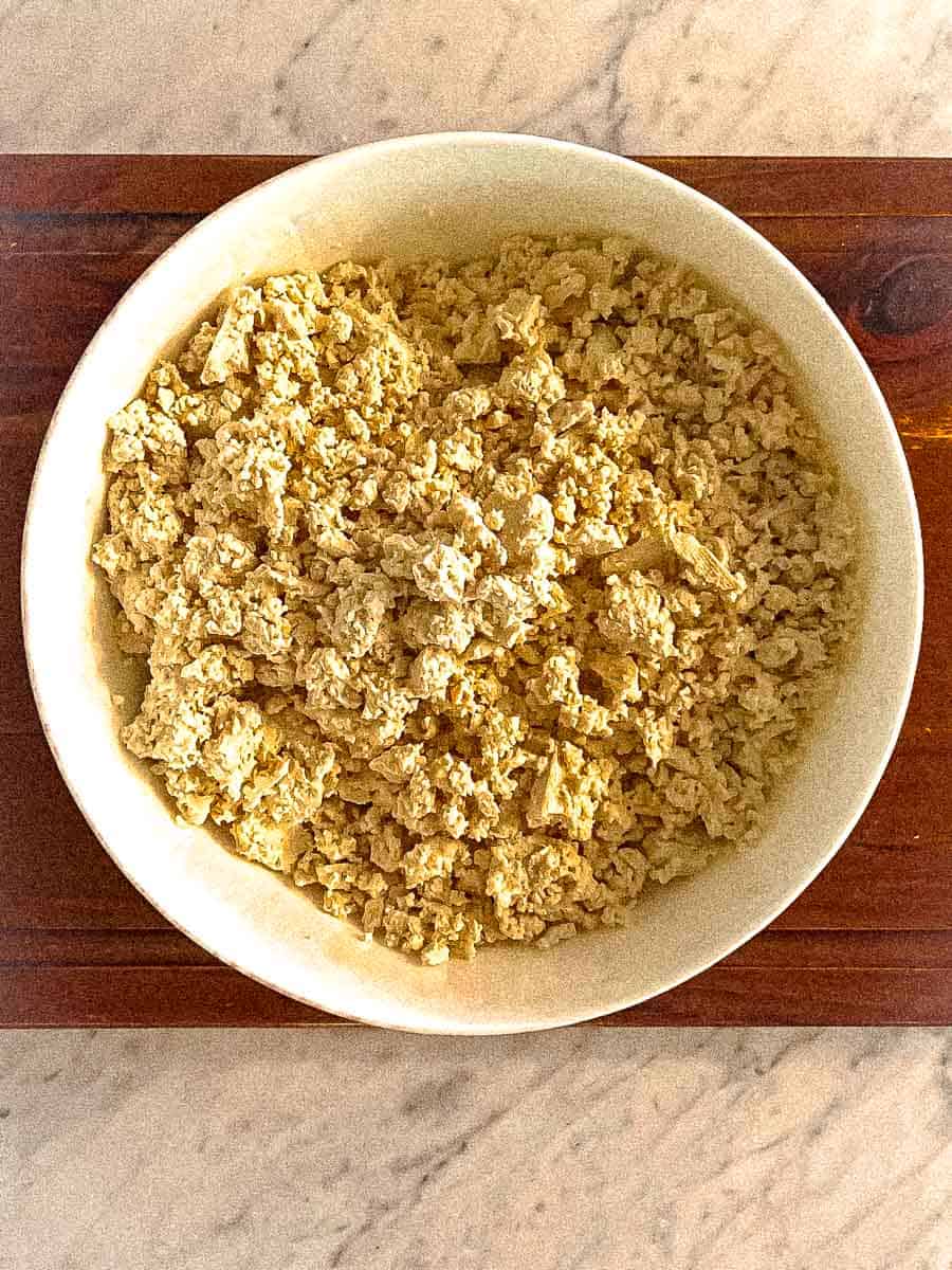 Two blocks of tofu crumbled in a bowl.