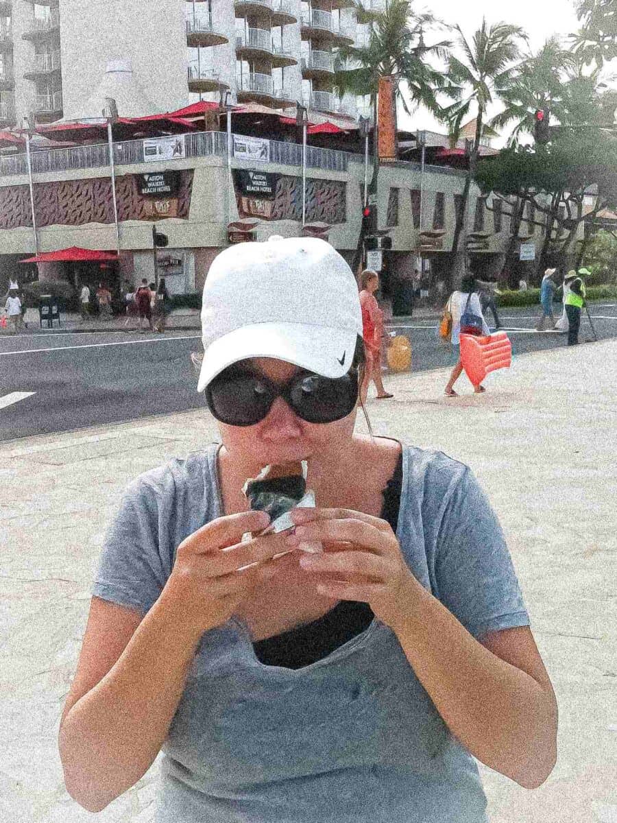 Anna eating her first spam musubi at Waikiki Beach