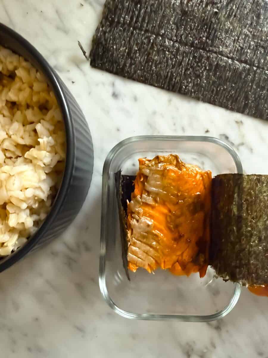 Salmon piece in the musubi mold with a strip of nori.