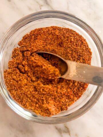 Prepared low sodium fajita seasoning in a glass bowl on a counter with a spoon in it.