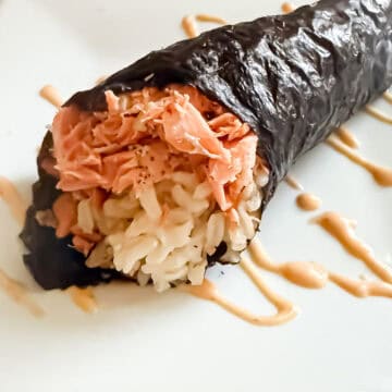 Prepared salmon hand roll on a plate with a drizzle of spicy mayo