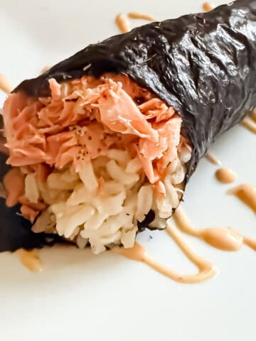 Prepared salmon hand roll on a plate with a drizzle of spicy mayo