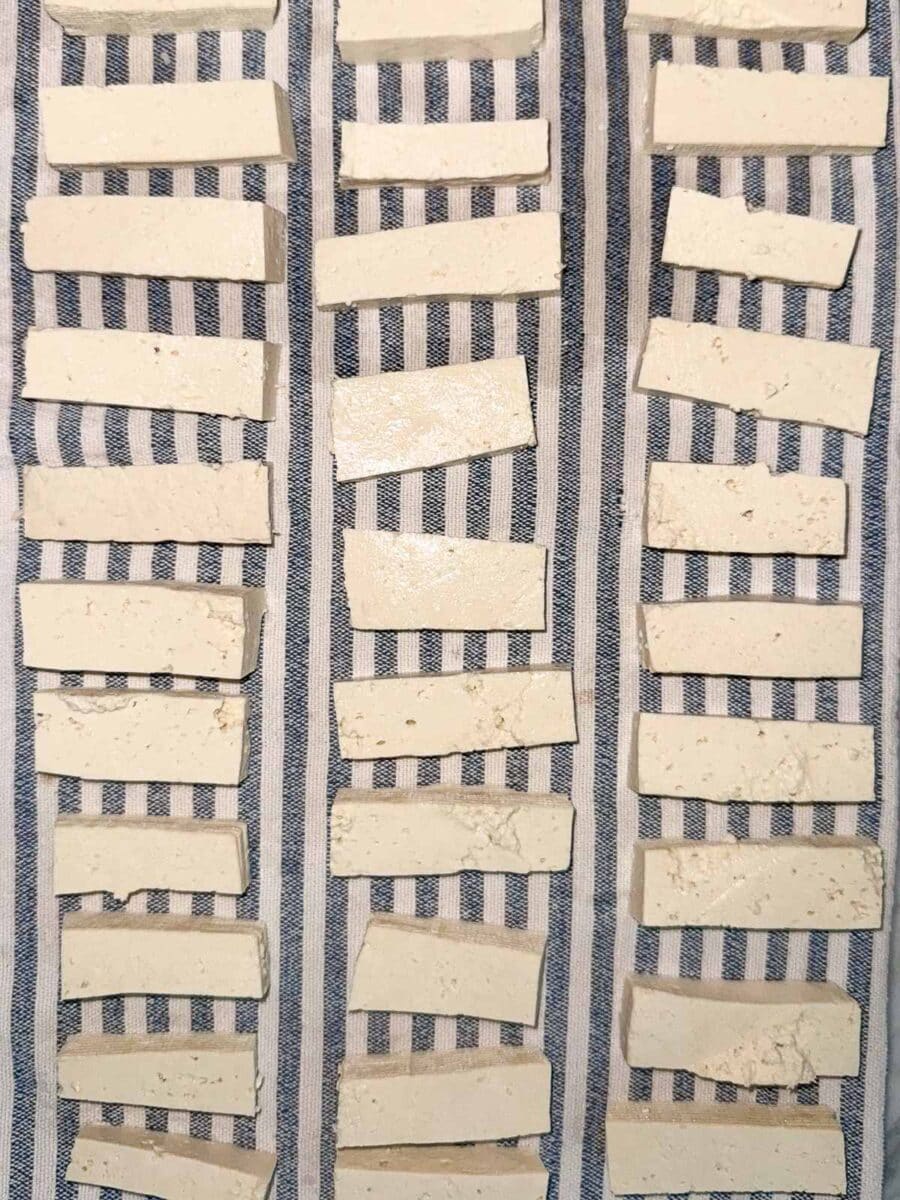 Raw tofu slices on a blue and white striped dishtowel.