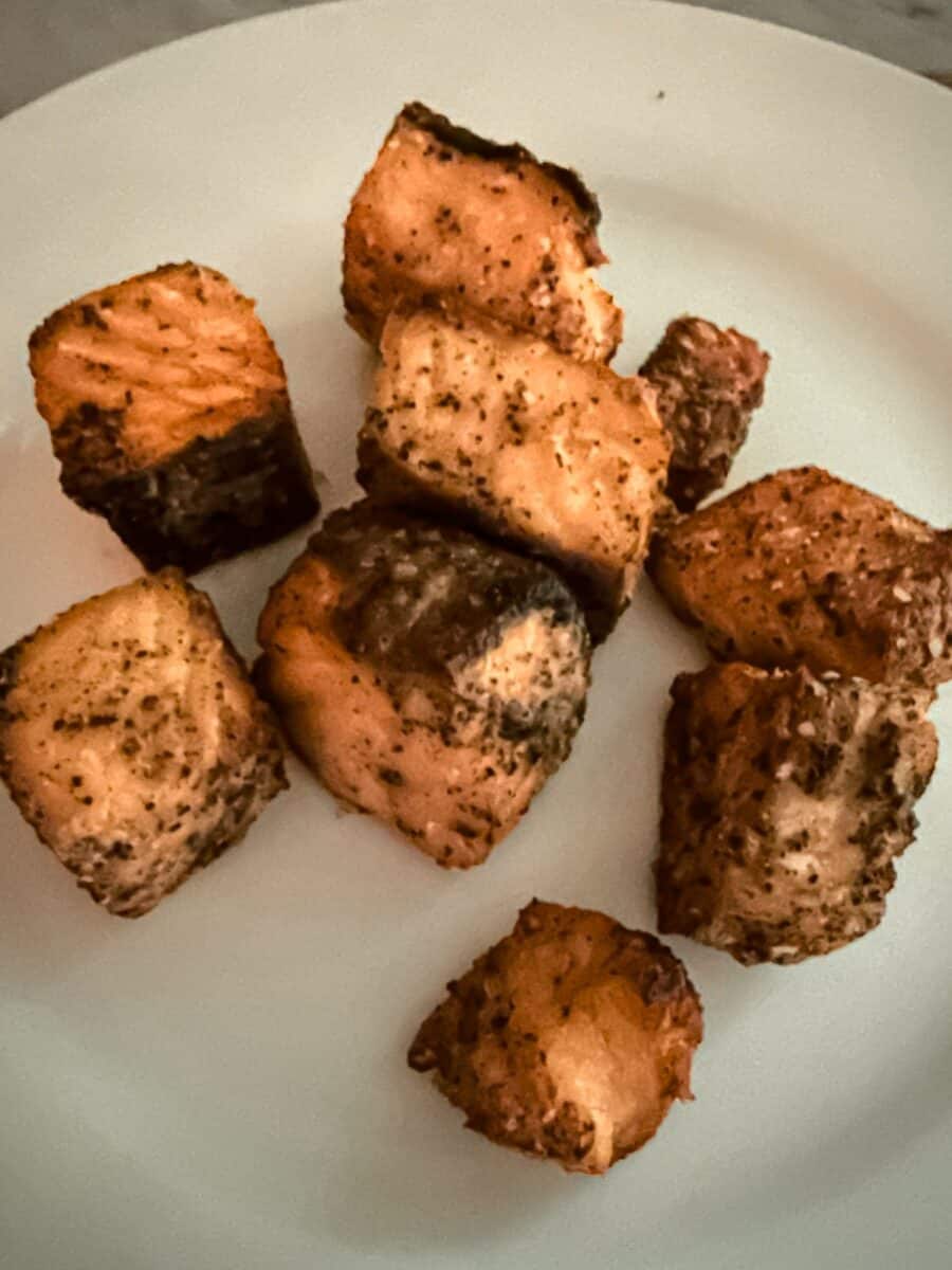 Bite sized chunks of crispy salmon on a white plate.