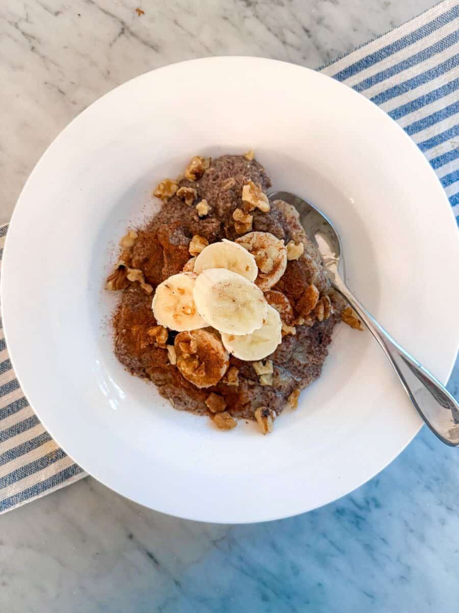 Creamy banana, flaxseed breakfast power bowl topped with walnuts, served in a white bowl. Perfect healthy omega-3 breakfast inspired by Mediterranean Diet and Portfolio Diet.