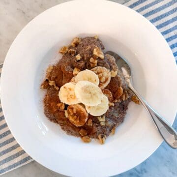 Creamy banana, flaxseed breakfast power bowl topped with walnuts, served in a white bowl. Perfect healthy omega-3 breakfast inspired by Mediterranean Diet and Portfolio Diet.