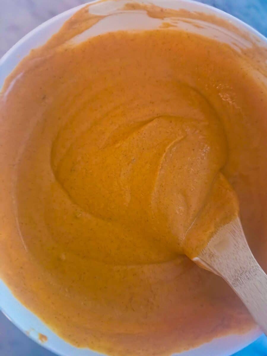 Pumpkin pie filling in a mixing bowl with a wooden spoon