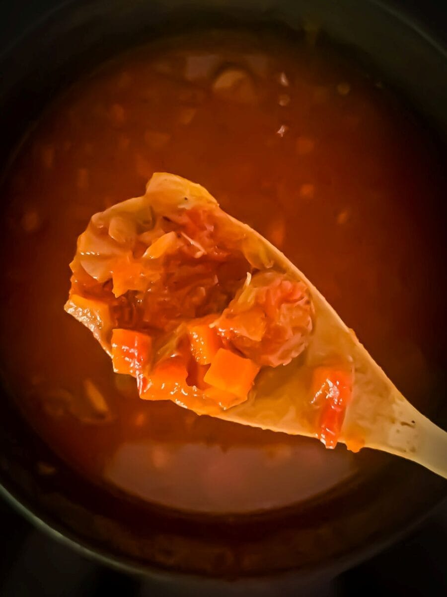 Mirepoix, sausage, chicken broth, and crushed tomatoes cooking together in step two of the Mediterranean Diet friendly Portuguese Bean Soup recipe.