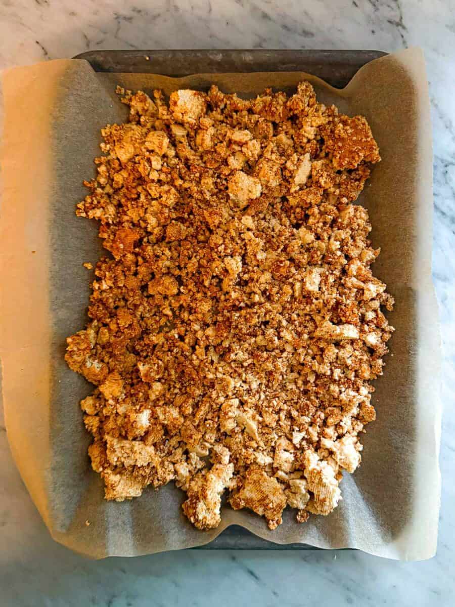 Crumbled tofu with taco seasoning on a parchment lined baking sheet