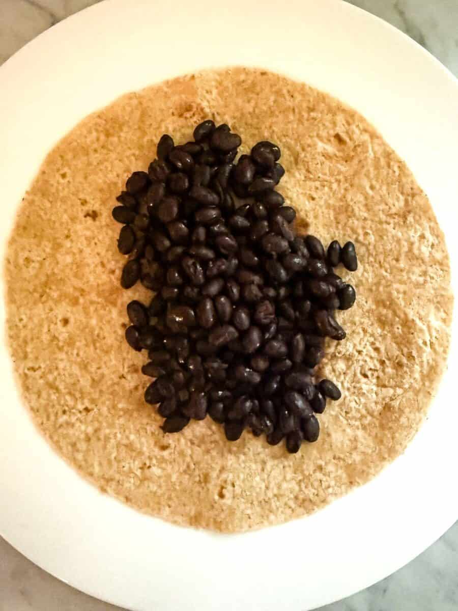 Step two of vegan taco recipe black beans on tortilla