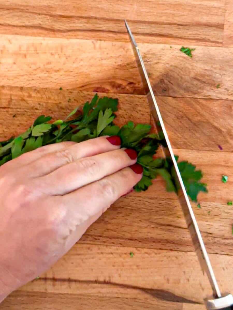 Cilantro being chopped on a wood cutting board