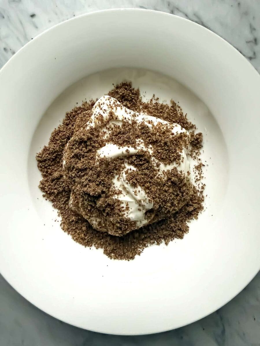 A bowl of plain, non-fat Greek yogurt topped with ground flax seed.