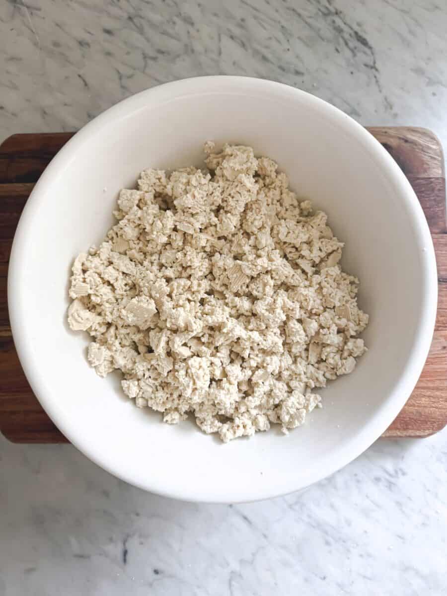 A white bowl containing crumbled tofu
