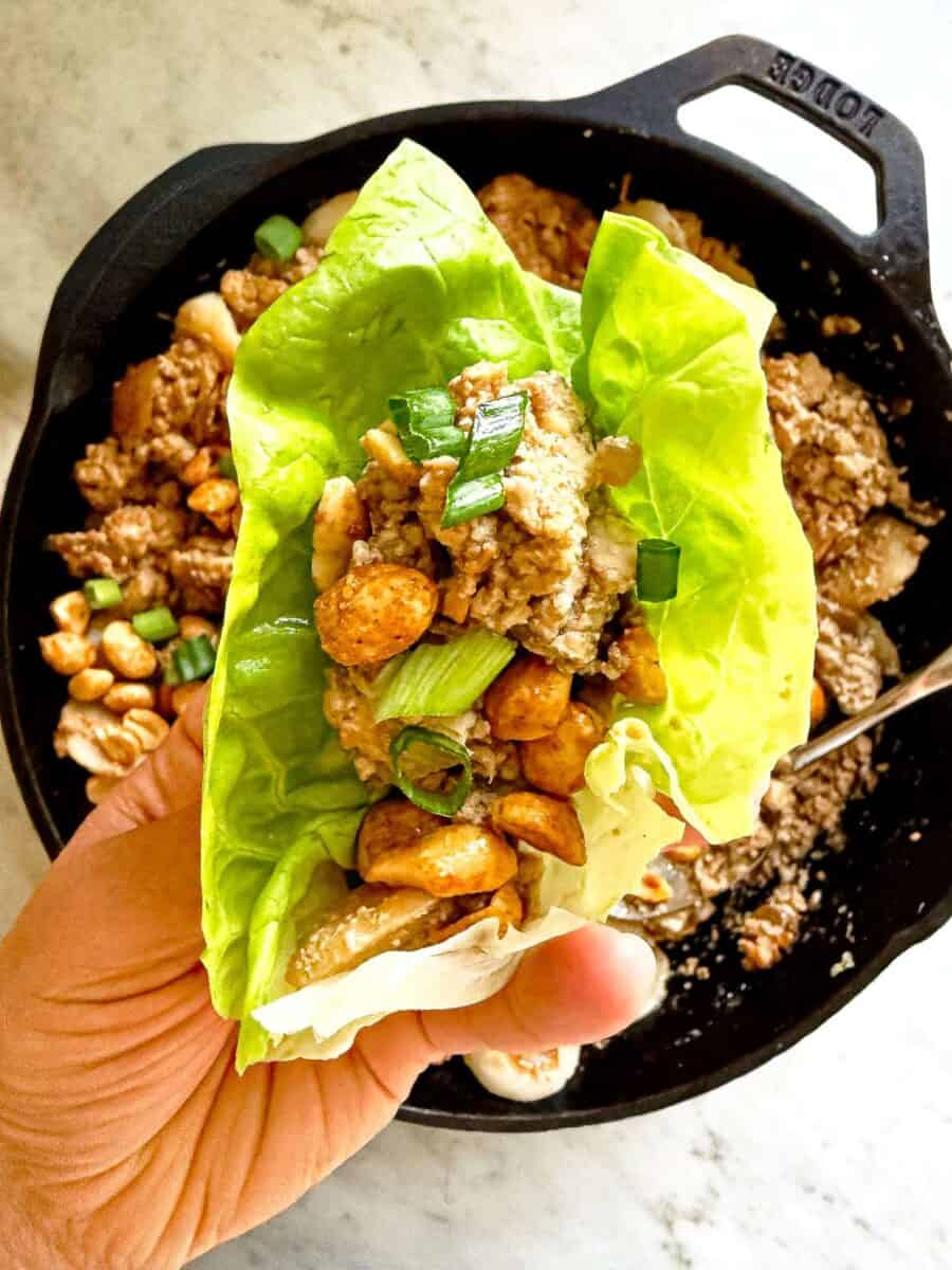 A prepared tofu lettuce wrap topped with green onions and peanuts