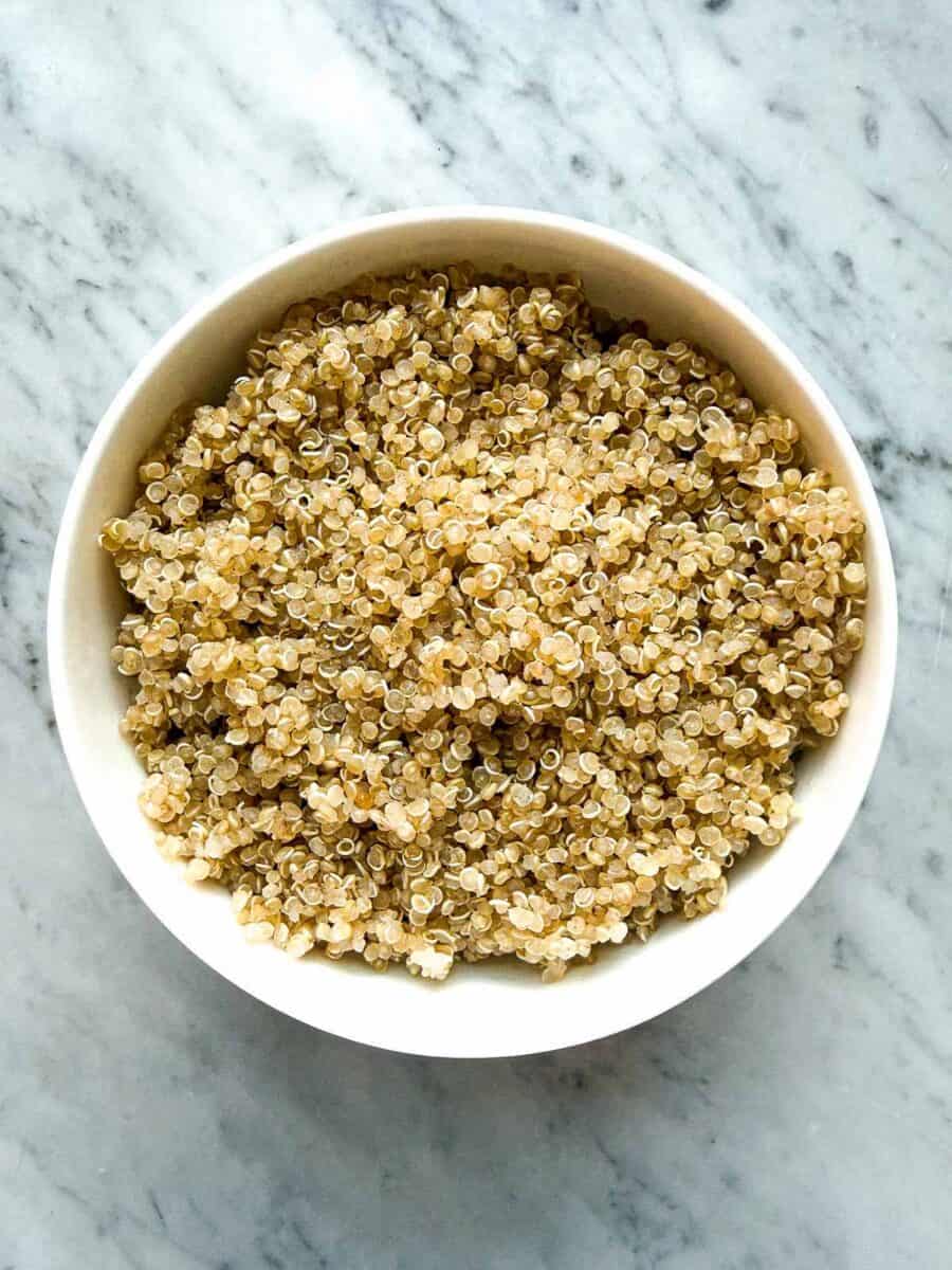 A bowl of white quinoa on a marble counter top
