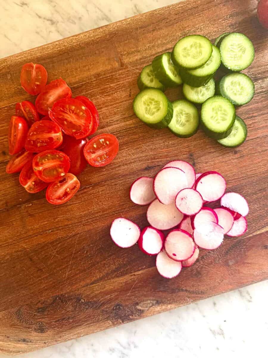tomatoes, radishes, and cucumbers all chopped on a cutting board