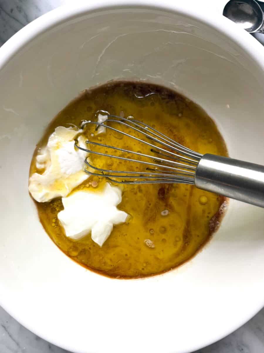 Wet ingredients for high protein blueberry muffins shown in a mixing bowl with a whisk