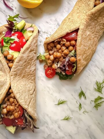 Mediterranean chickpea wraps filled with marinated chickpeas, mixed greens, tomatoes, cucumber, red onion, tzatziki, and fresh dill.