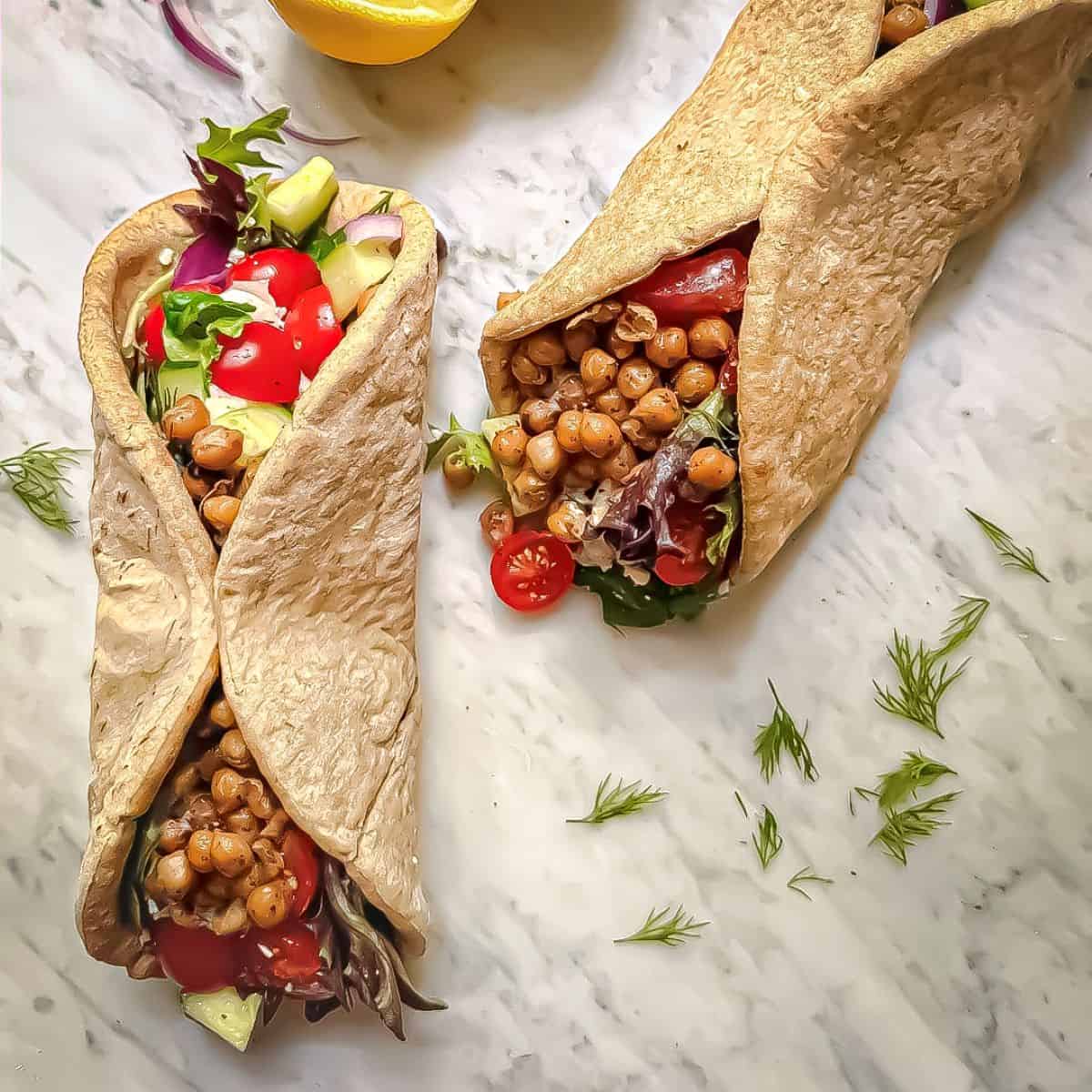 Mediterranean chickpea wraps filled with marinated chickpeas, mixed greens, tomatoes, cucumber, red onion, tzatziki, and fresh dill.