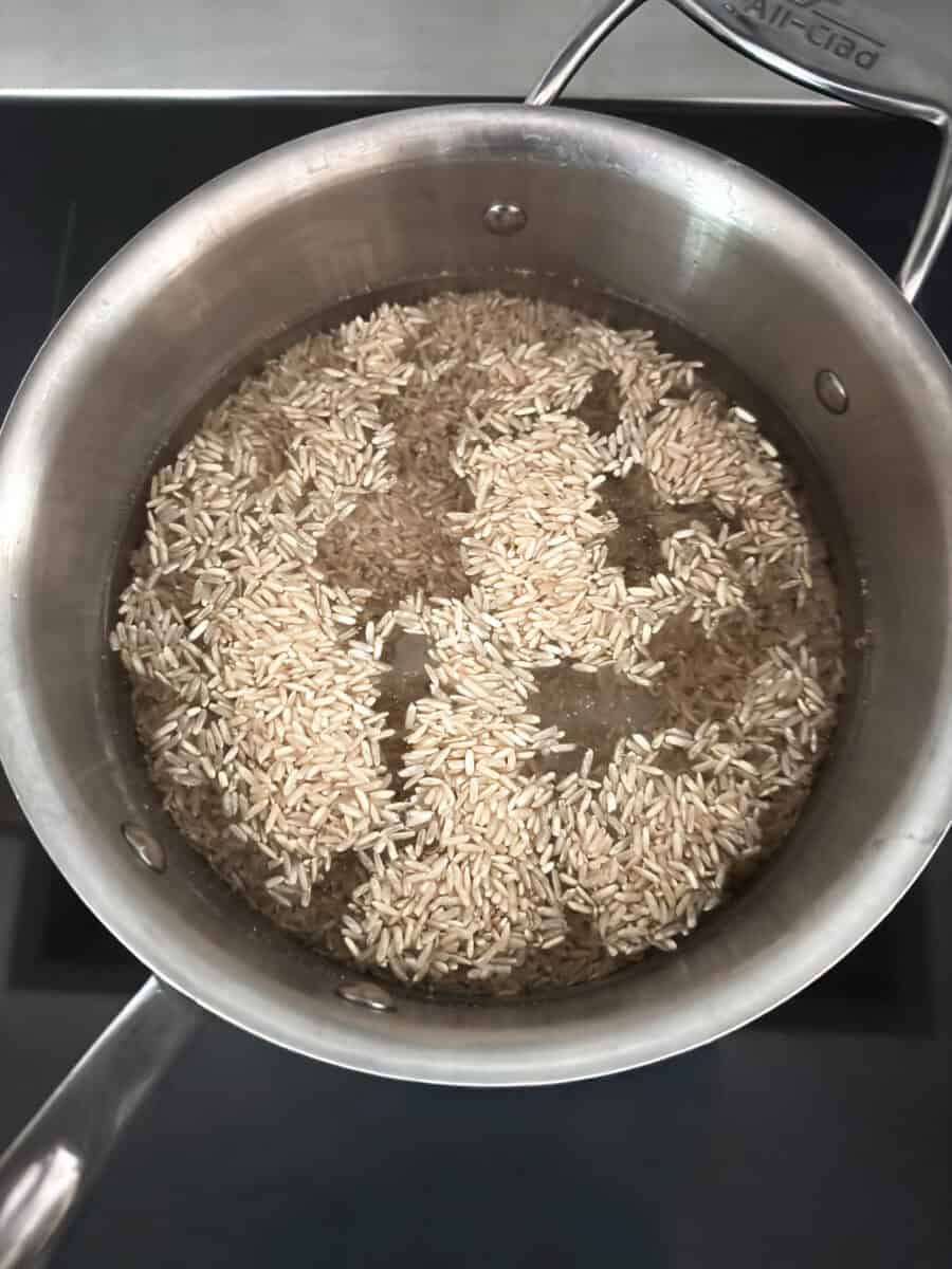 Brown rice cooking in a saucepan for a cooked salmon poke bowl.