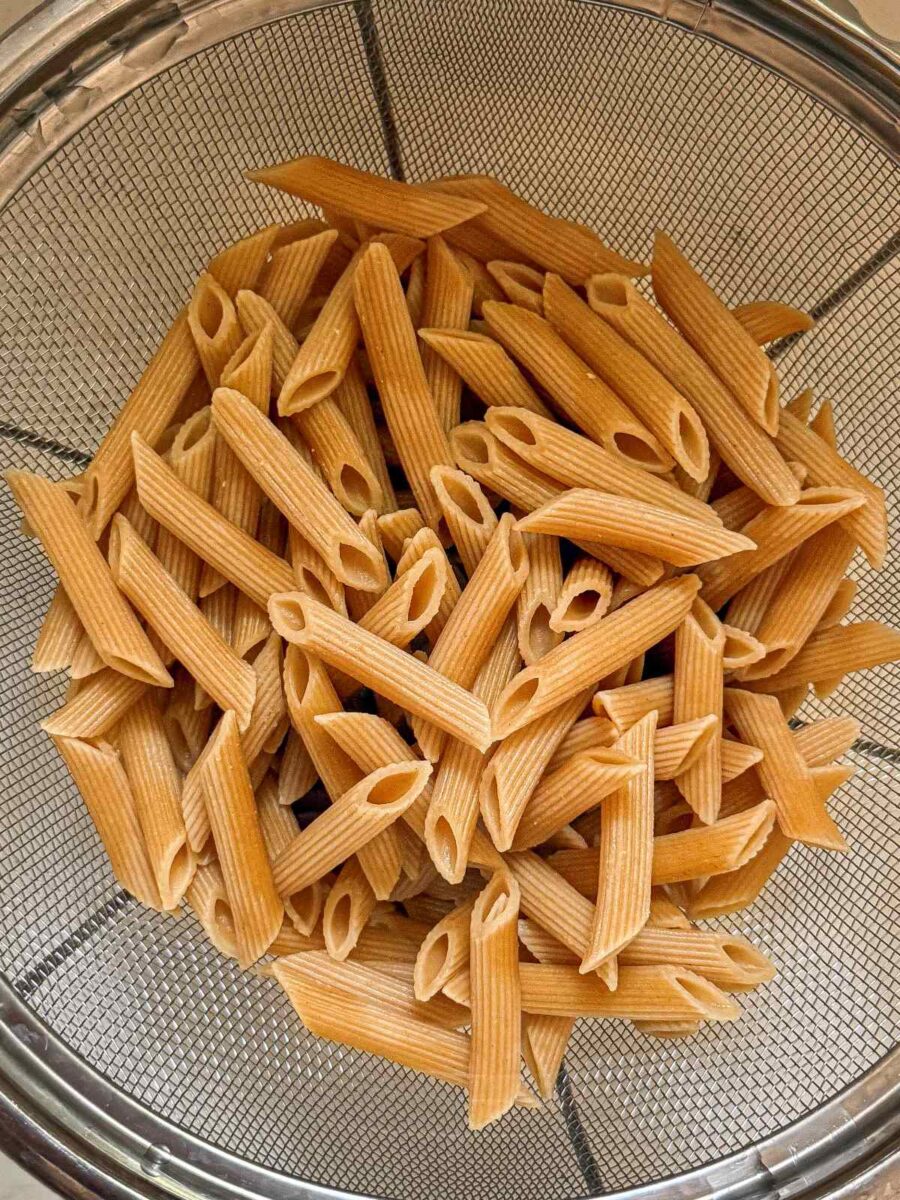 Cooked whole wheat penne noodles in a collander.