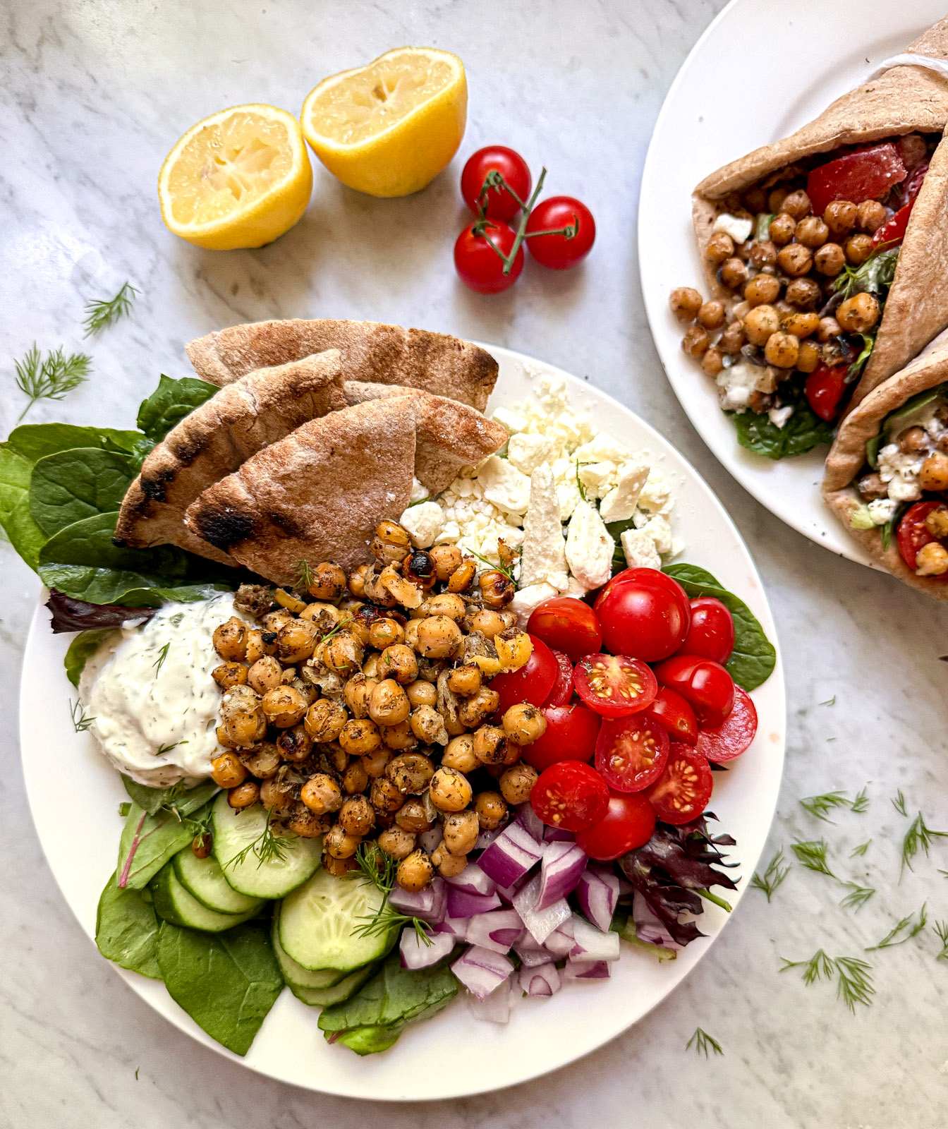 Mediterranean chickpea salad with marinated chickpeas, mixed greens, tomatoes, cucumber, red onion, reduced fat feta, tzatziki, dill, and whole grain pita.